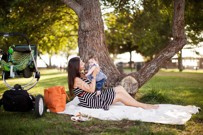 Mother sitting on picnic blanket with baby daughter — Stock Photo