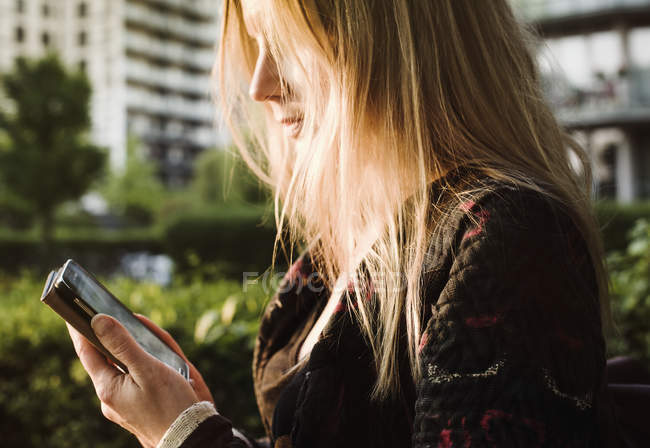 Mujer joven al aire libre, usando teléfono inteligente - foto de stock