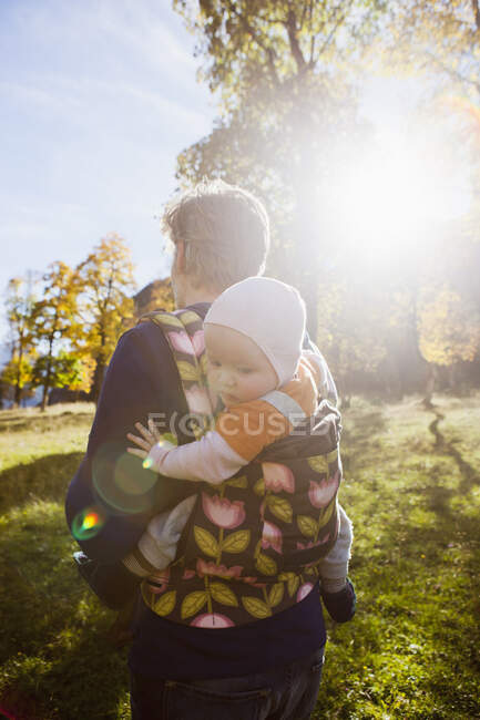 Father carrying baby daughter in carrier — Stock Photo