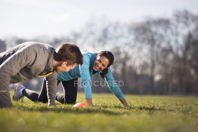 Young man and woman doing push up training on playing field — Stock Photo