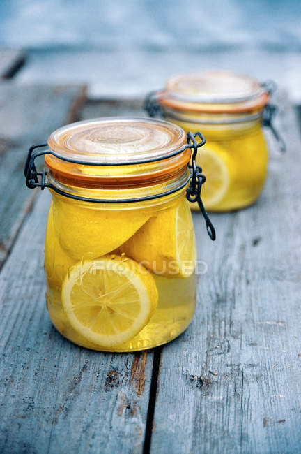 Jar of lemons in juice on rustic wooden surface — Stock Photo