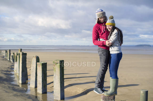 Parejas jóvenes de pie en groynes, Brean Sands, Somerset, Inglaterra - foto de stock