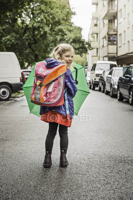 Young schoolgirl carrying umbrella — Stock Photo