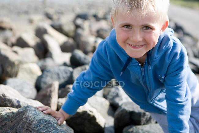 Niño sentado en piedras - foto de stock