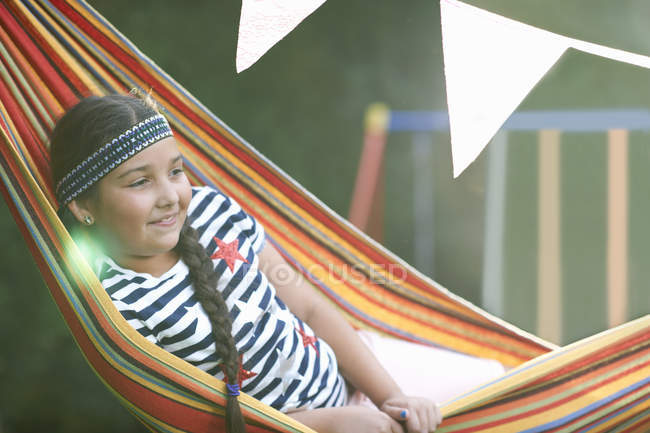 Ritratto di ragazza carina con fascia per capelli e treccia reclinabile in amaca da giardino a righe — Foto stock