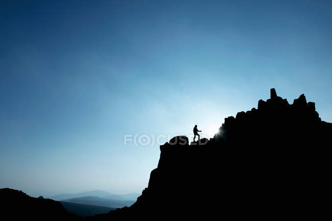 Hombre de senderismo en la ladera rocosa - foto de stock