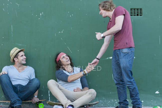 Tres amigos varones adultos reunidos en la calle - foto de stock