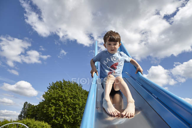 Junge stürzt Spielplatzrutsche herunter — Stockfoto