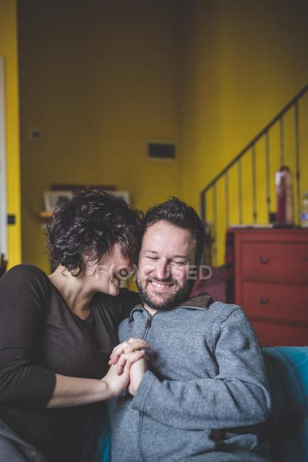 Пара сидить на дивані, тримаючись за руки — стокове фото