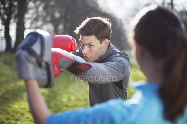 Young man and woman doing boxing training in park — Stock Photo