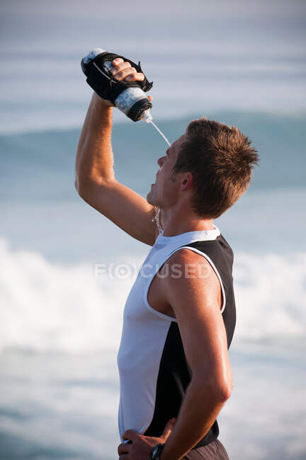 Läufer schüttet sich am Strand Wasser auf den Kopf — Stockfoto