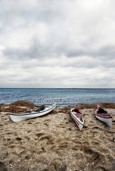 Kayaks en la playa de arena con cielo nublado - foto de stock