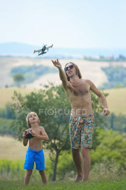Pai e filho voando avião de controle remoto, ao ar livre — Fotografia de Stock