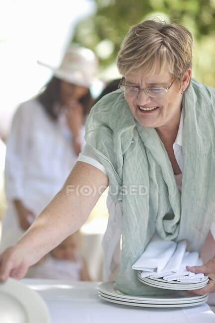 Старша жінка встановлює стіл — стокове фото
