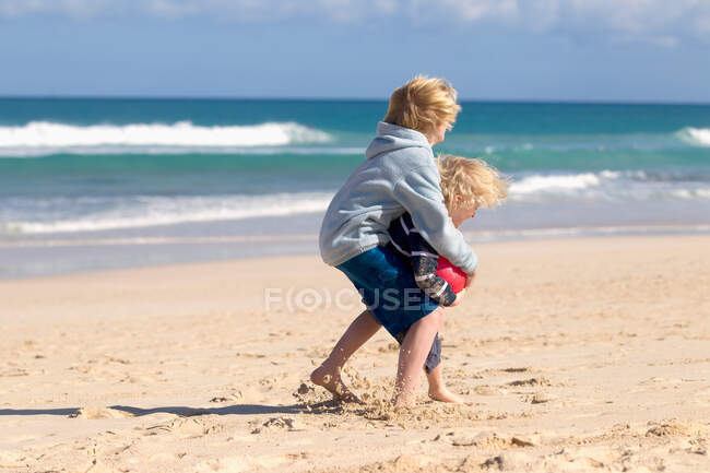 Jungen spielen mit rotem Ball am Strand — Stockfoto