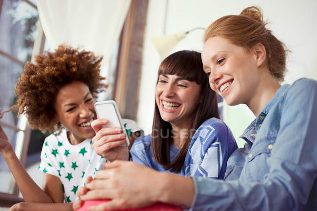 Tres amigas usando smartphone - foto de stock