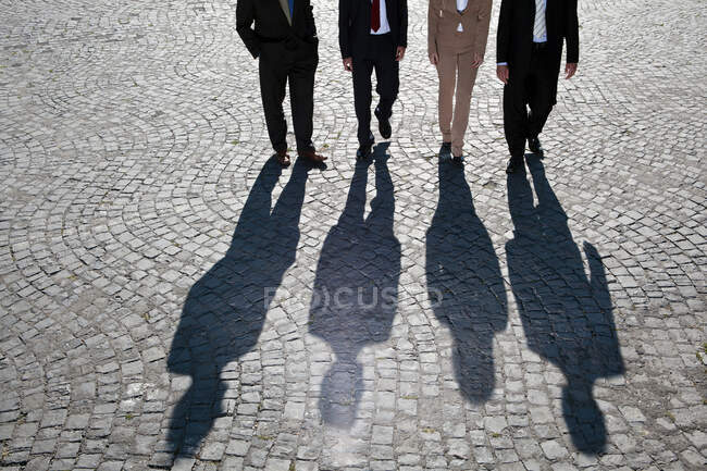 Shadows walking on cobbled road — Stock Photo