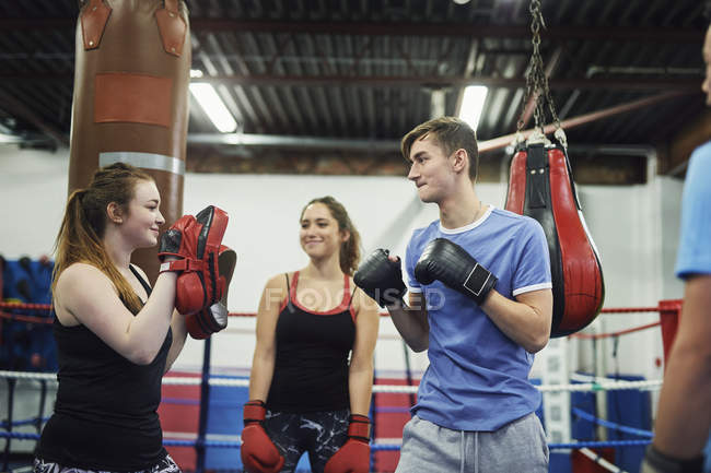 Male boxer training, poised to punch teammates punch mitt — Stock Photo