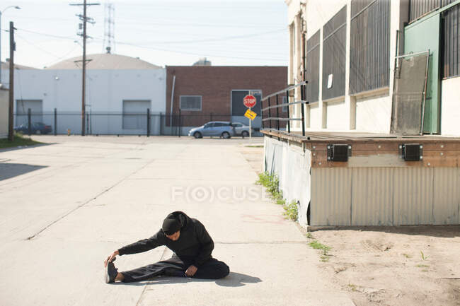 El hombre se estira en el entorno urbano - foto de stock