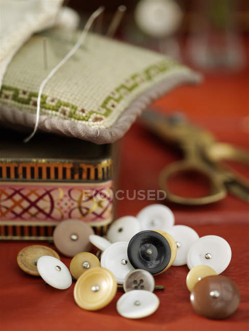 Vintage buttons and pin cushion on red table — Stock Photo