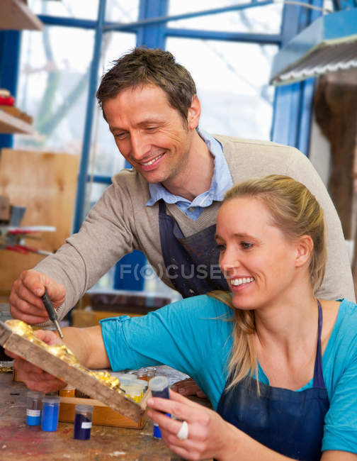 Carpintero trabajando con asistente en tienda - foto de stock