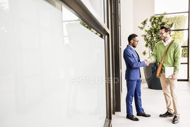 Два бизнесмена пожимают руки за пределами офисного здания — стоковое фото
