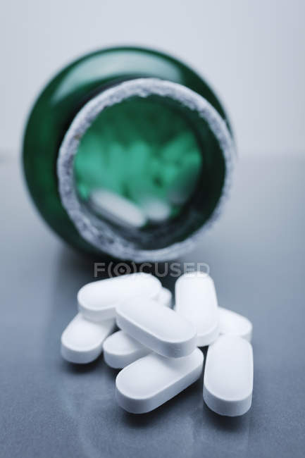 Pílulas médicas espalhadas sobre frasco, close-up tiro — Fotografia de Stock