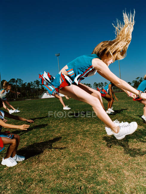 Young cheerleaders performing routine on football field — Stock Photo