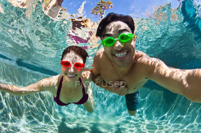 Casal jovem nadando debaixo d 'água na piscina — Fotografia de Stock