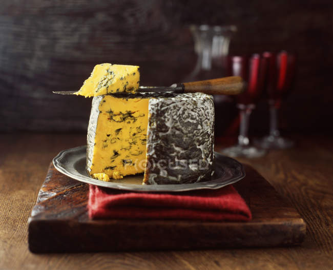 Чорні палички синій сир круглий на дерев'яній обробній дошці з сирним ножем — стокове фото