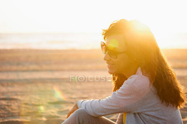 Усміхнена жінка в сонцезахисних окулярах на пляжі — стокове фото