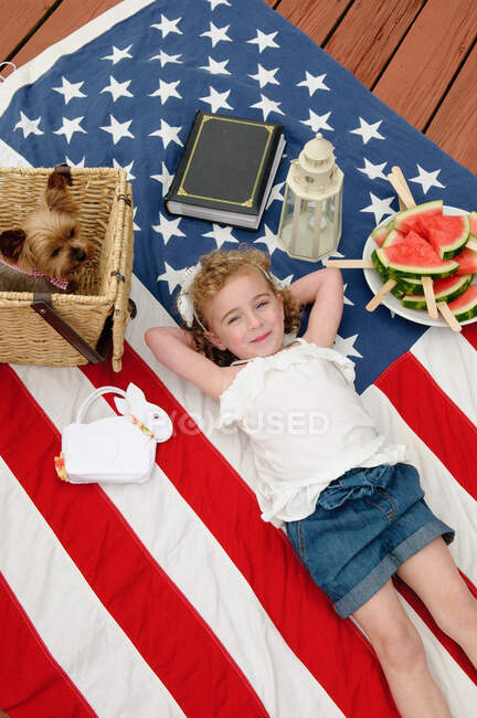 Menina deitada na bandeira dos EUA com cão — Fotografia de Stock