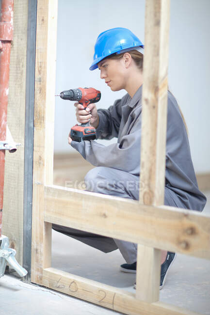 Trabalhadora feminina usando broca elétrica no canteiro de obras — Fotografia de Stock