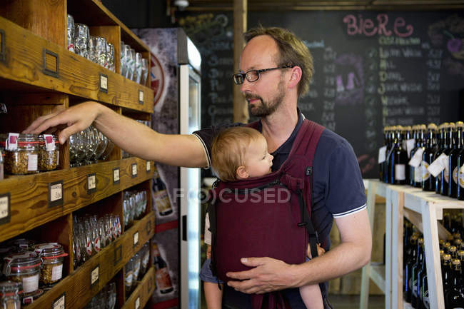 Padre con hija bebé mirando frascos en la tienda - foto de stock