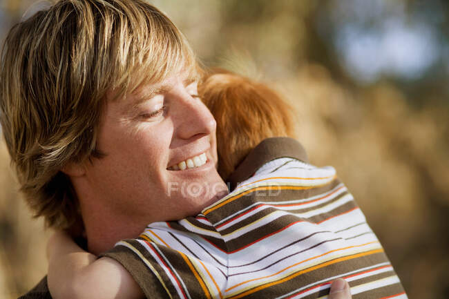 Sonriente padre sosteniendo joven hijo - foto de stock