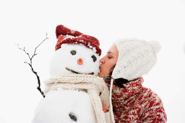 Donna che bacia pupazzo di neve in inverno — Foto stock