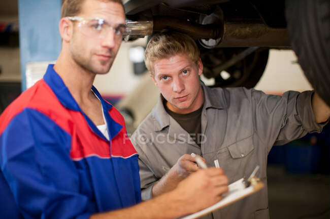 Mecânica do carro discutindo e analisando reparação automóvel — Fotografia de Stock