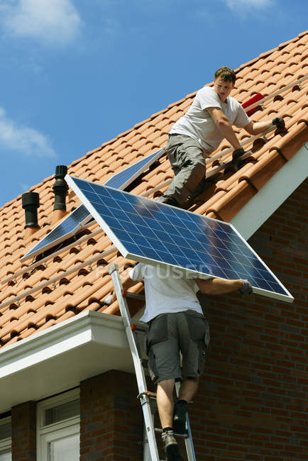 Workers carrying and installing solar panels on roof of new home, Netherlands — Stock Photo