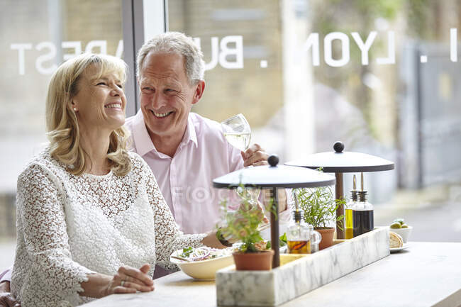 Mature dating couple laughing at restaurant lunch, London, UK — Stock Photo