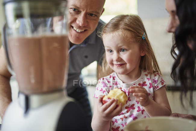 Family watching smoothie in blender smiling together — Stock Photo