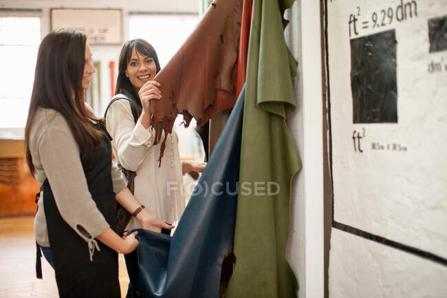 Shop assistant and customer looking at leather — Stock Photo