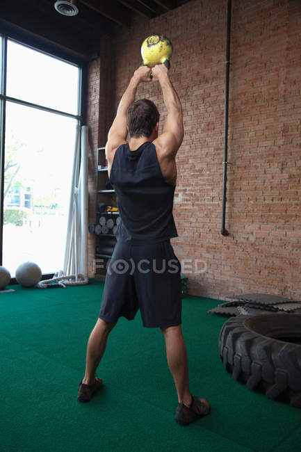 Masculino fisiculturista levantamento kettlebells no ginásio — Fotografia de Stock