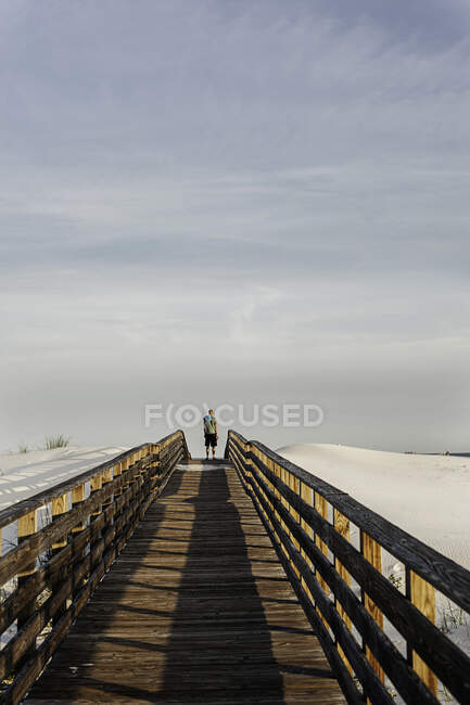 Jeune homme sur une passerelle en bois surélevée, Côte du Golfe, Alabama, États-Unis — Photo de stock