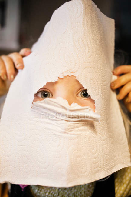 Retrato de niña mirando aunque agujero en la toalla de cocina - foto de stock