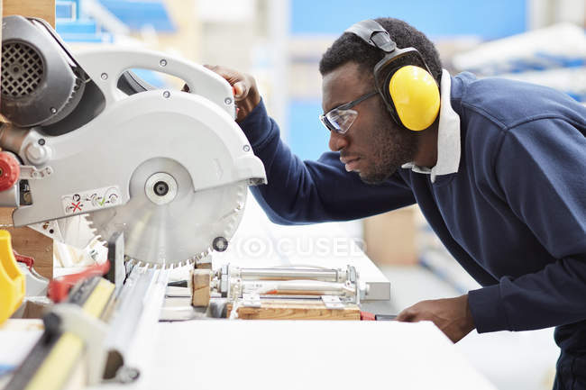 Factory worker using circular saw in roller blind factory — Stock Photo