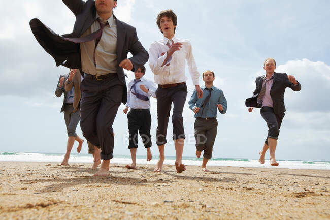 Businessmen running on beach — Stock Photo