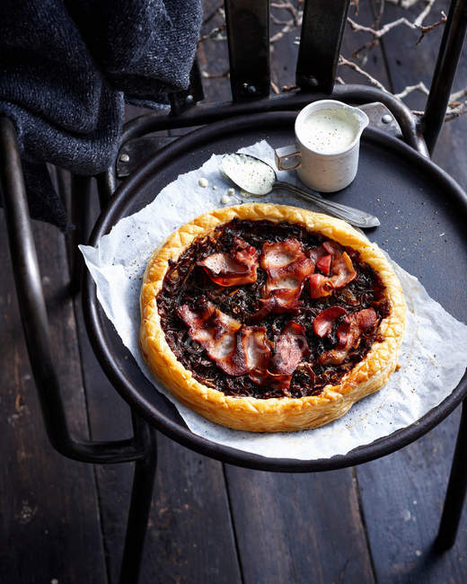 Bacon and onion tart with spoon and cream in jug — Stock Photo