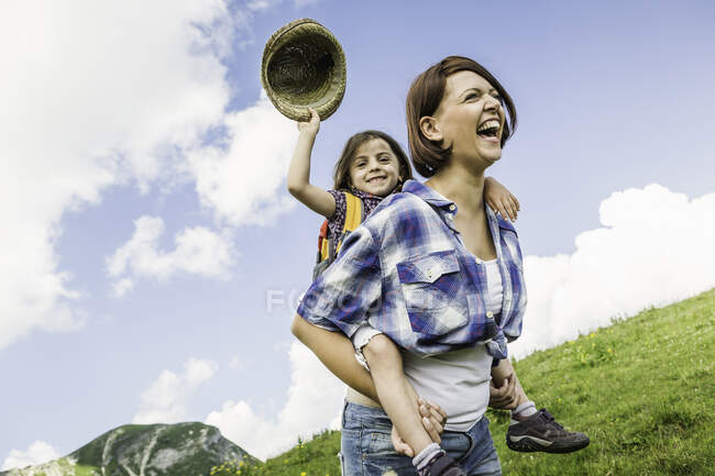 Mother and daughter on hike, girl holding straw hat — Stock Photo