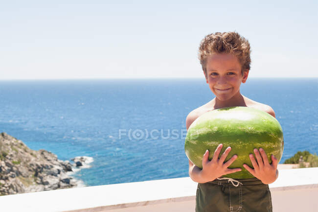 Niño sosteniendo sandía en balcón - foto de stock