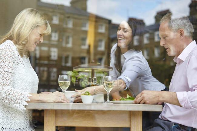 Waitress serving lunch to mature dating couple at restaurant table, London, UK — Stock Photo